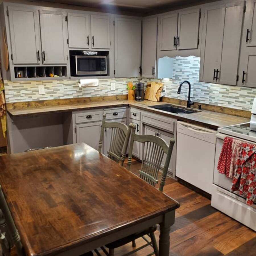 Farmhouse-style kitchen with butcher block island, light cabinetry, and red checkered towels