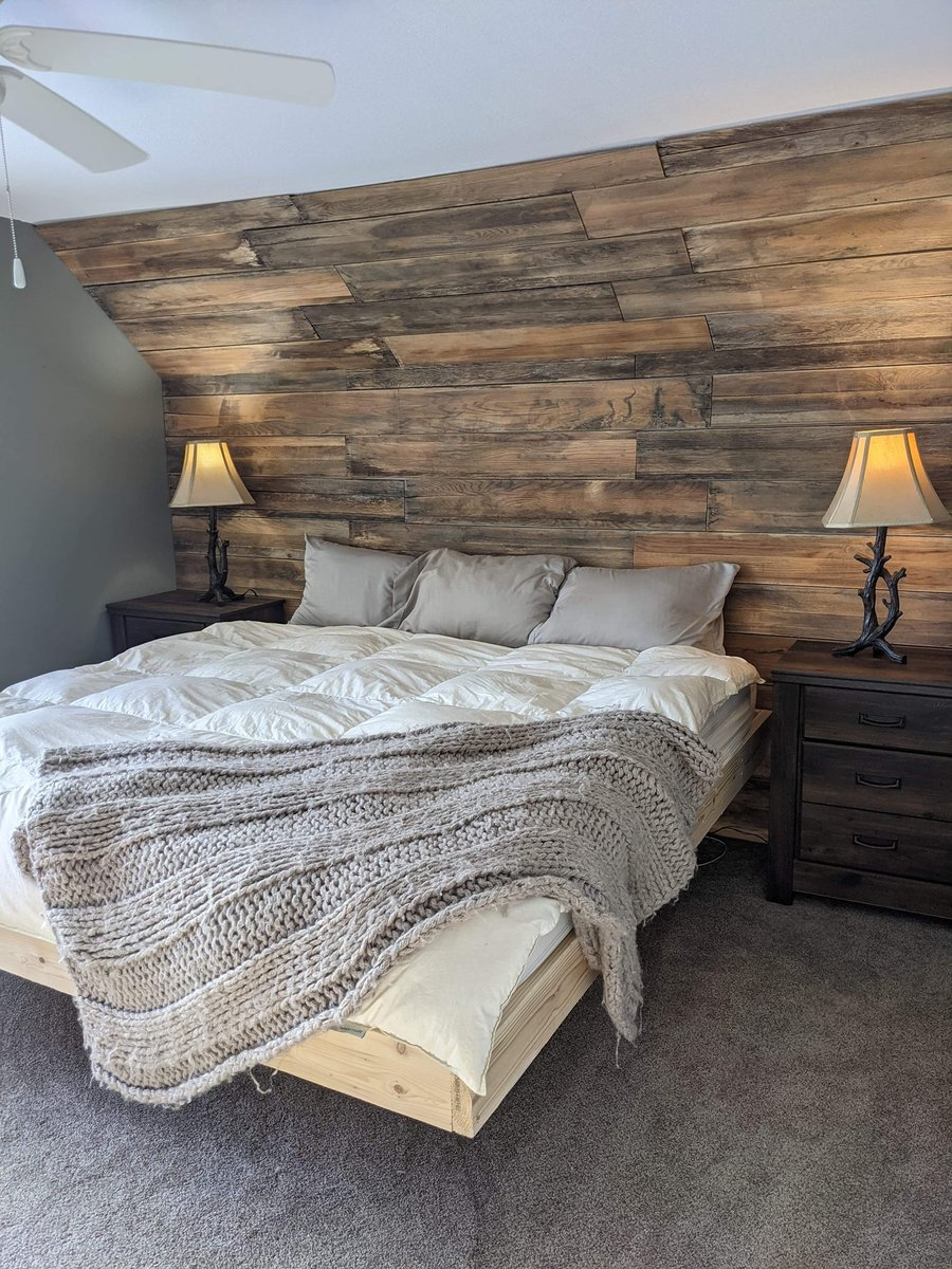 Rustic bedroom with wood panel accent wall, bed, and side tables with lamps