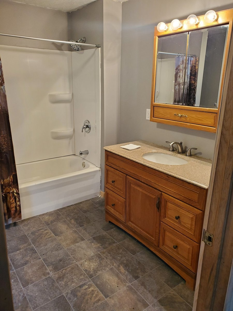Bathroom with walk-in tub, brown wood vanity, and a white shower curtain