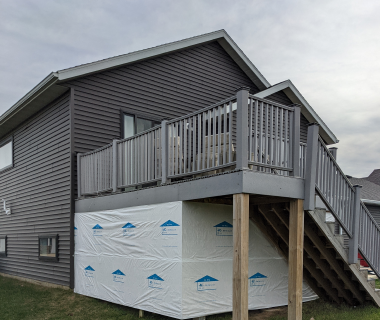 Home exterior with partially completed deck and house wrap on lower level