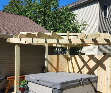 View of wooden pergola structure being installed next to a hot tub