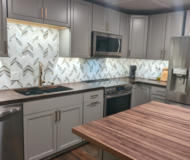 Modern gray kitchen with chevron backsplash and wooden dining table